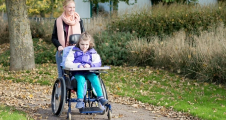 Aide pushing girl in wheelchair